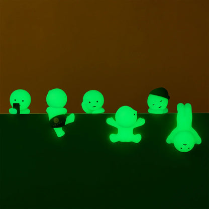 Glowing green figures sitting on a ledge against a brown background